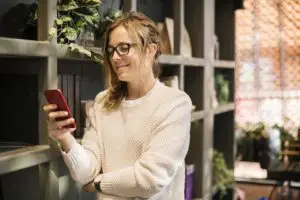 A woman looking at her phone while trying to buy a house remotely.